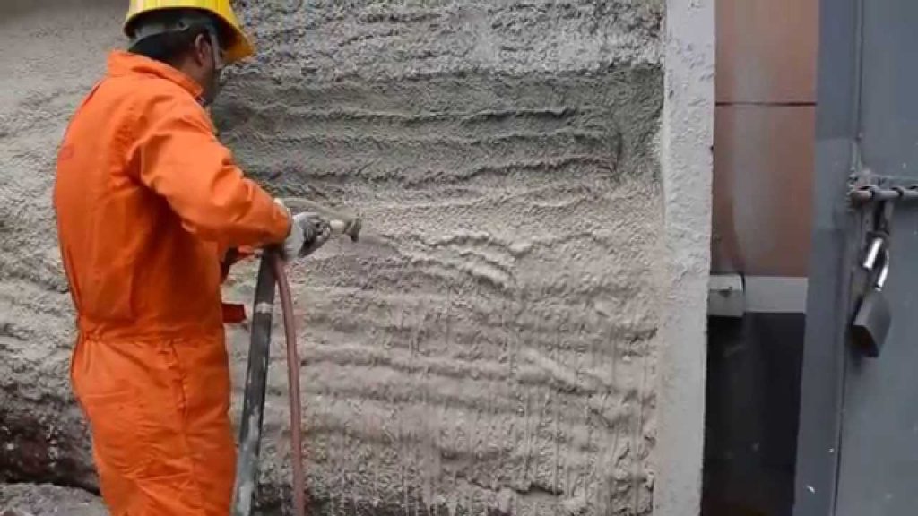 Strojní nanášení omítky na fasádu budovy